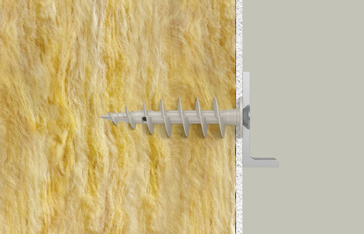 Une vis est tournée à travers une couche d'isolation jaune dans un mur gris. Un morceau de métal maintient la vis stable.