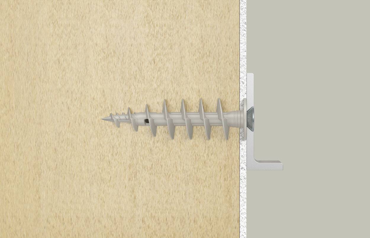 Un chevillet en plastique gris avec une vis est fixé dans une planche en bois et vissé dans un mur gris adjacent.