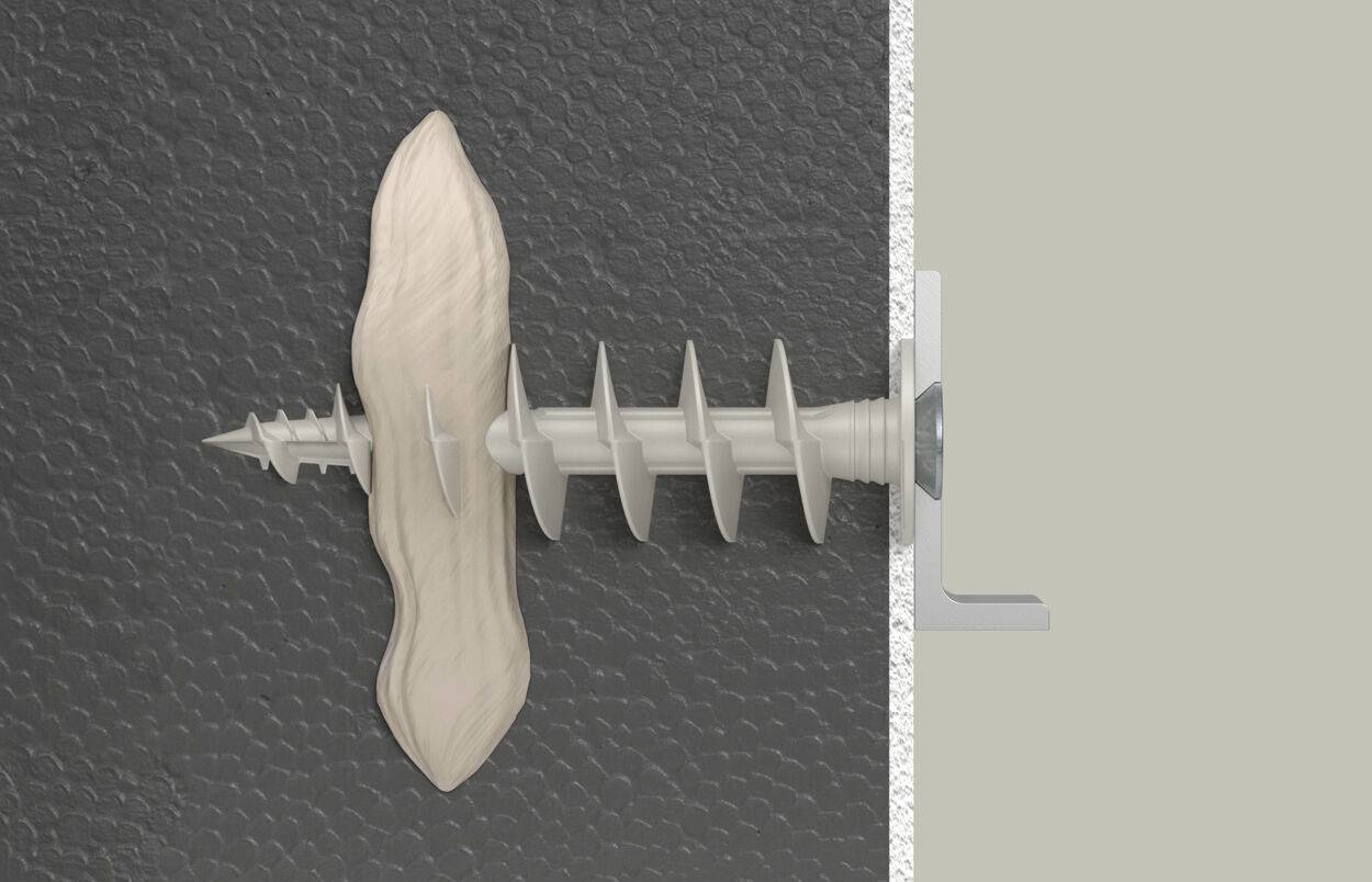 Une cheville escargot est vissée à travers un morceau de bois et un mur. La cheville possède un filetage en spirale.