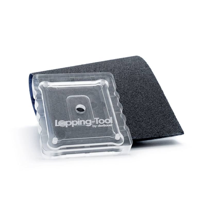 Outil de meulage sur papier de verre, utilisé pour le traitement de surface. Un boîtier en plastique transparent est posé sur du papier sombre.