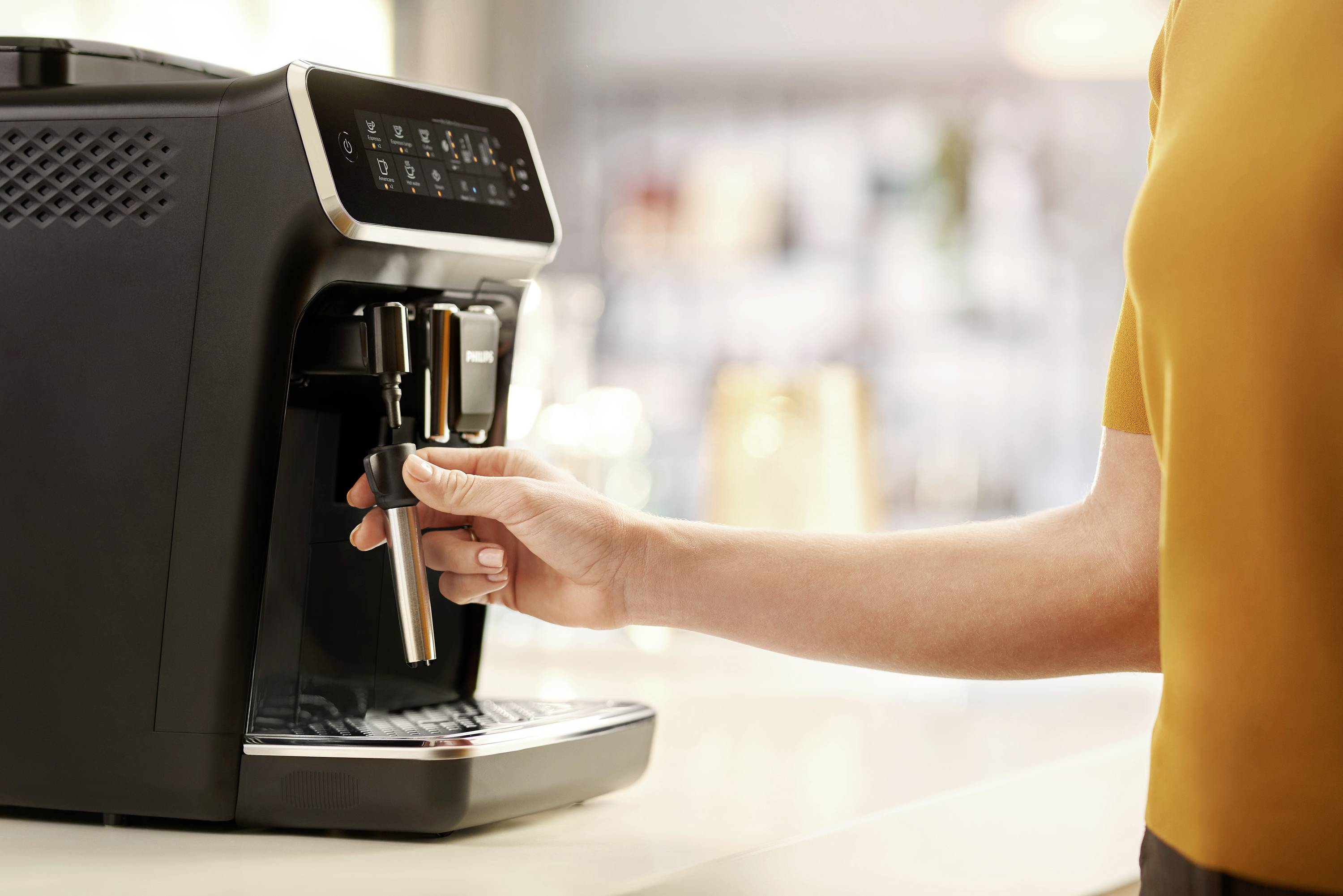 Une personne utilise une machine à café moderne dans une cuisine. La main actionne le levier pour préparer du café.