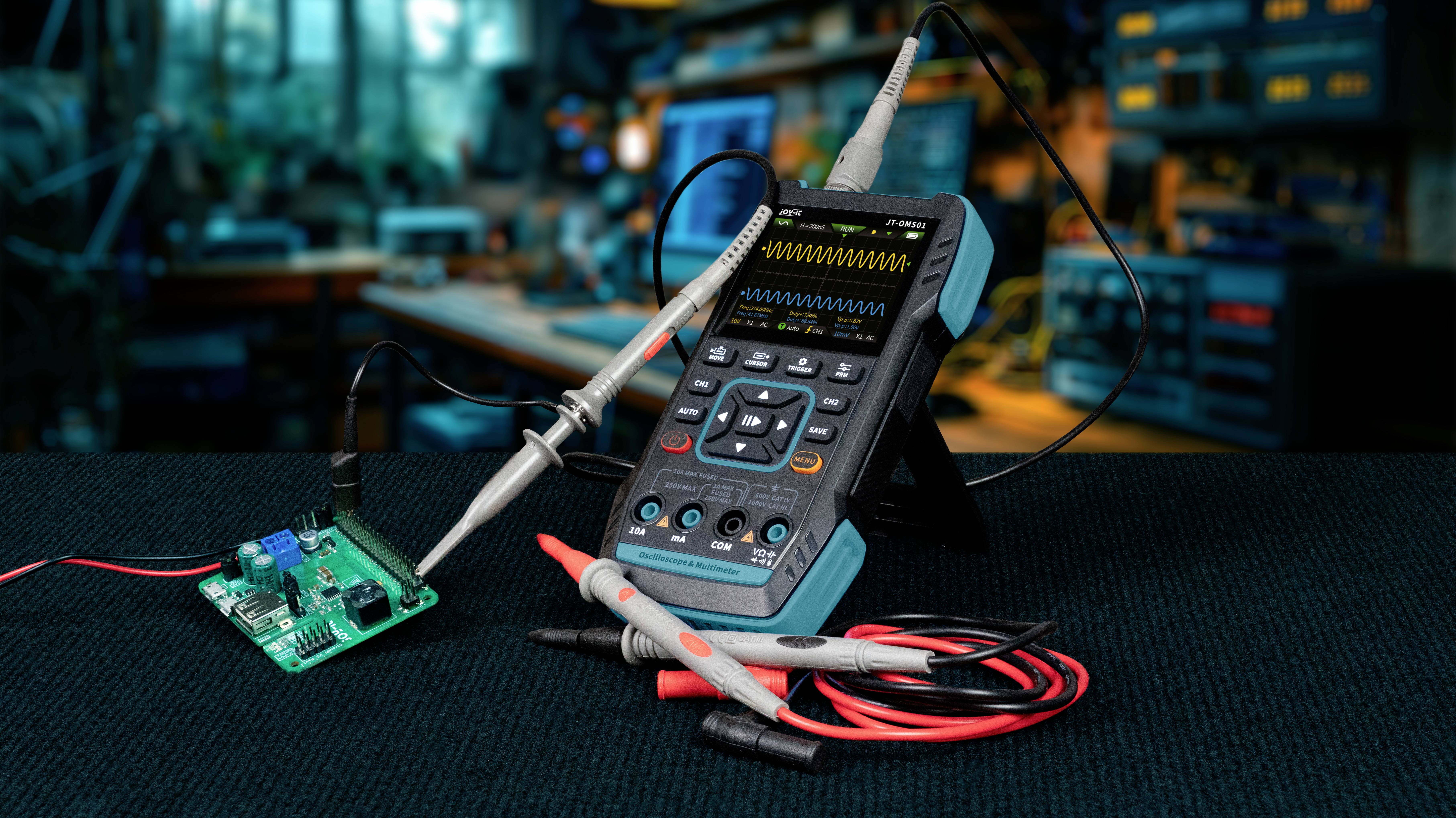 Un oscilloscope est posé sur une table dans un atelier, relié à un circuit électronique. Des outils et des appareils sont visibles en arrière-plan.