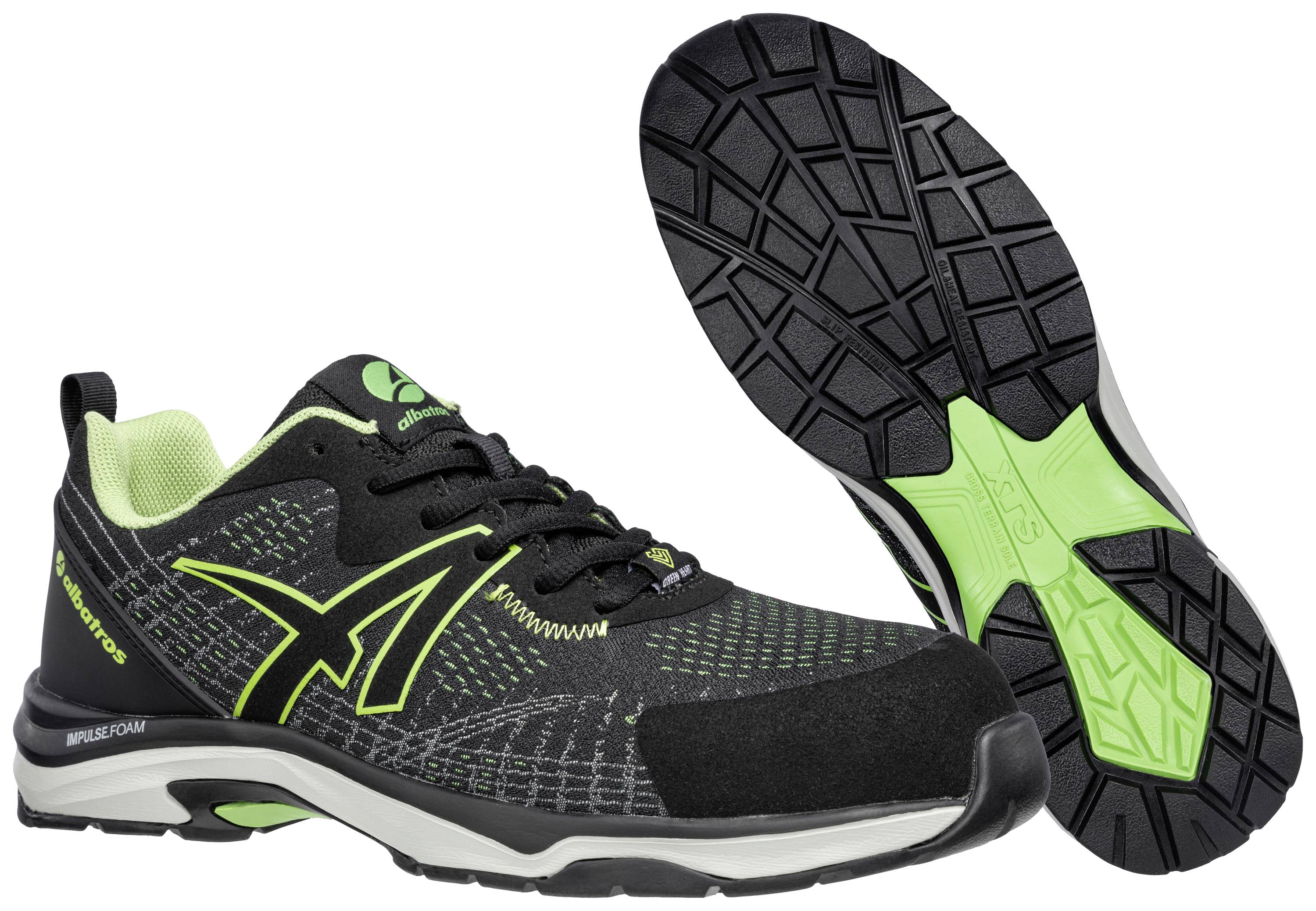 Chaussures de sport noires avec des accents verts et des semelles robustes. Adaptées aux activités de plein air.