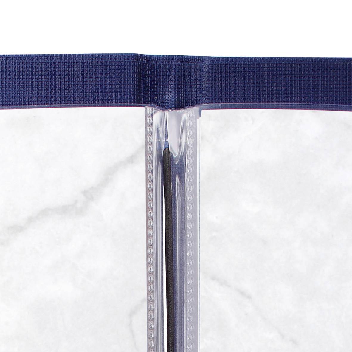 Un livre ouvert aux pages gris clair et à la couverture bleu foncé est posé à plat sur une surface en marbre blanc.