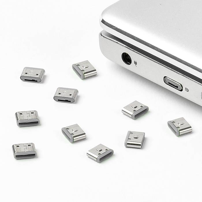 Un ordinateur portable avec plusieurs adaptateurs USB sur une surface blanche, montrant ses possibilités de connexion polyvalentes.