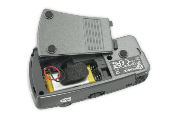 Un appareil électronique ouvert révélant son intérieur, comprenant une batterie et des fils, sur un fond blanc.