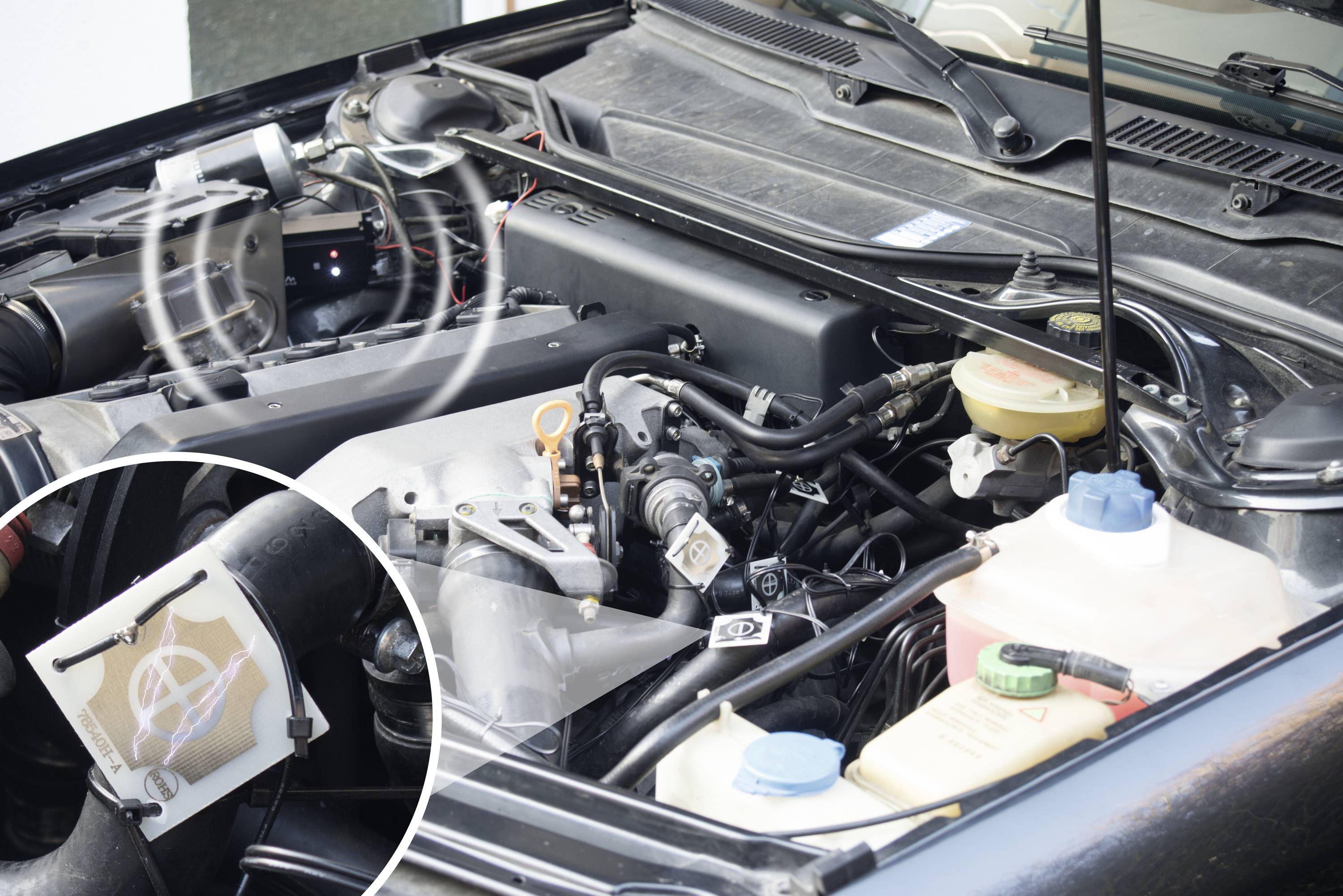Un radiateur de voiture ouvert avec des tuyaux visibles et des réservoirs de liquide de refroidissement. Un agrandissement montre le maillage du radiateur.