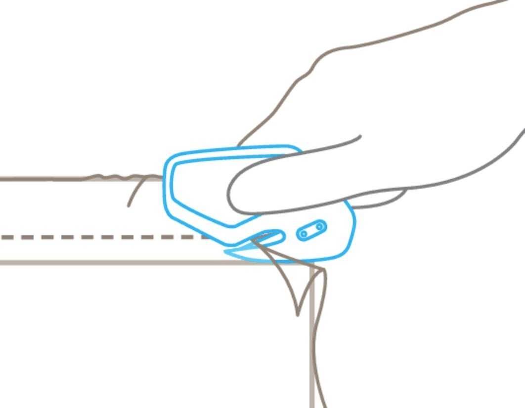 La main utilise un coupe-fil pour couper le fil le long d'une ligne pointillée sur le bord du tissu.