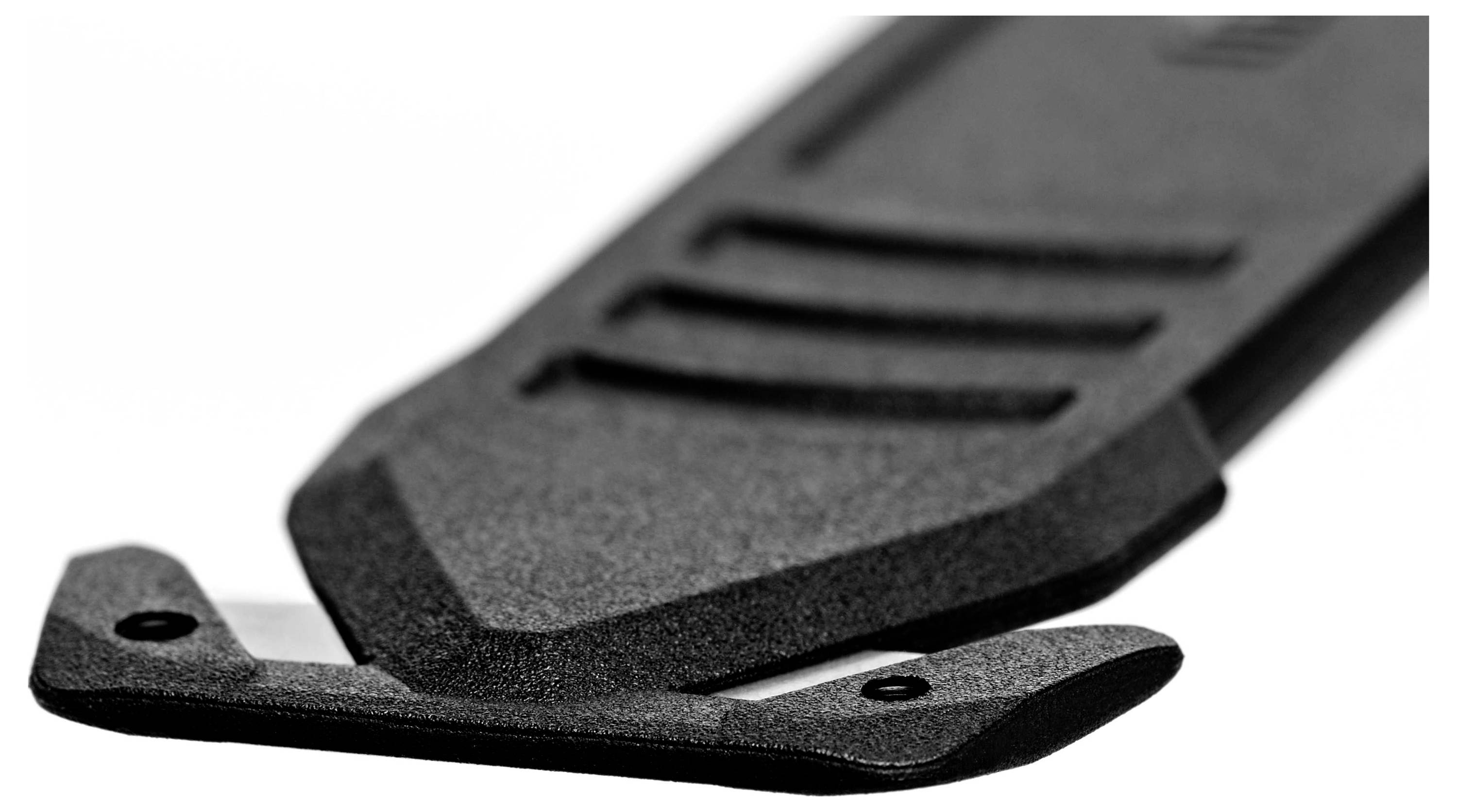 Couteau à tapis noir avec lame sortie, montrant un gros plan détaillé du design et de la texture.