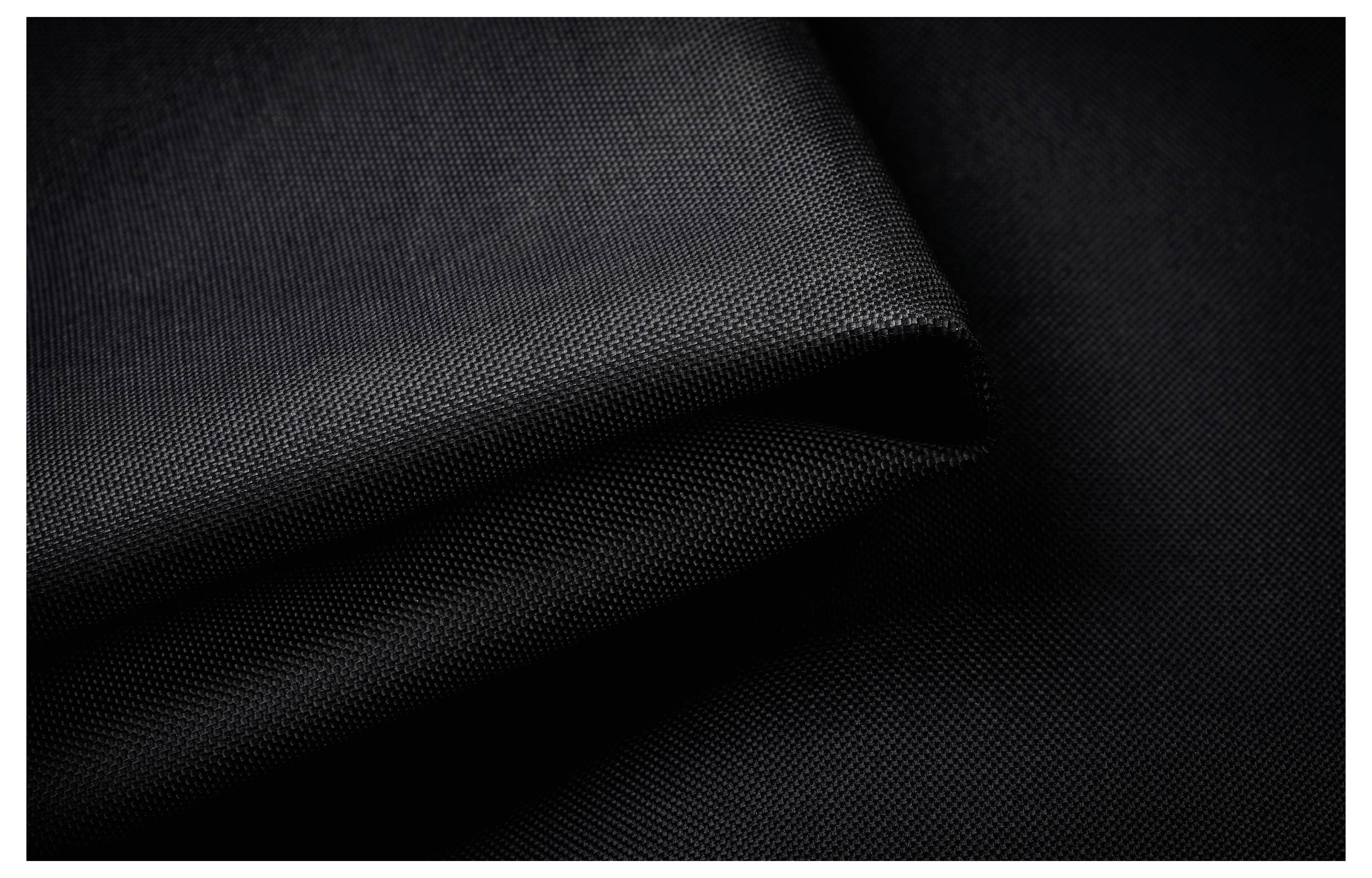 Gros plan d'un tissu noir plié, révélant une texture subtile et détaillant sa couleur et ses nuances de surface.