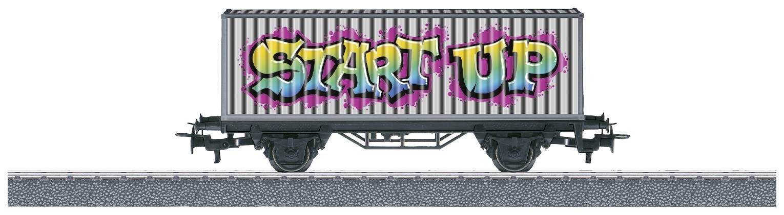 Camion de fret avec des graffitis du mot 'START UP' en couleurs vives sur le côté, stationné sur une section de voie ferrée.