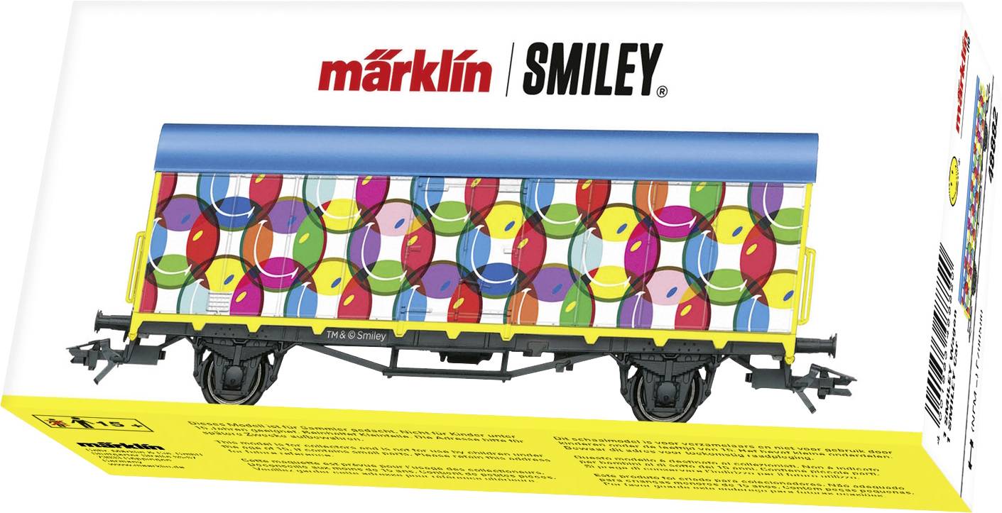 Un wagon de marchandises coloré avec des smileys joyeux et un toit bleu dans un emballage portant l'inscription « märklin SMILEY ».