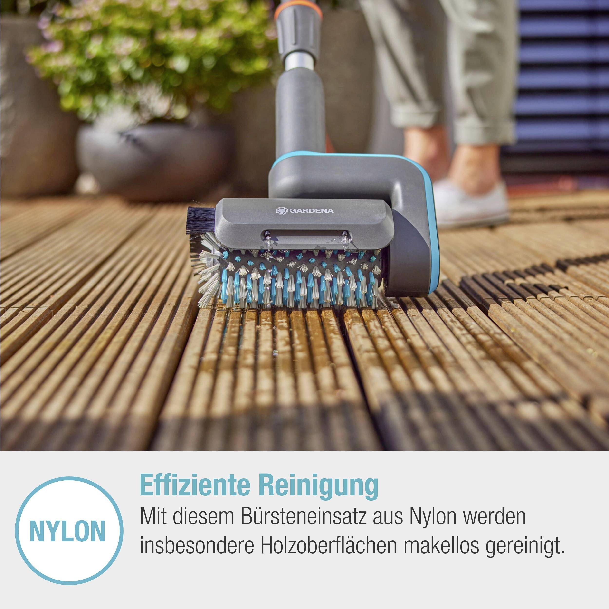 Une personne nettoie un plancher en bois avec une brosse en nylon de Gardena. Gros plan sur la brosse passant sur les lames de bois. Nettoyage efficace.