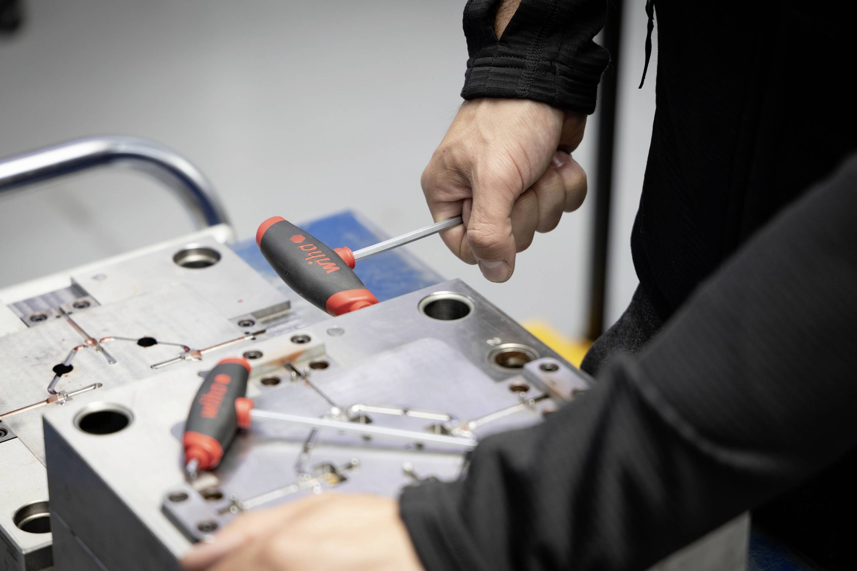 'Gros plan d'un mécanicien travaillant avec des tournevis sur une machine métallique.'