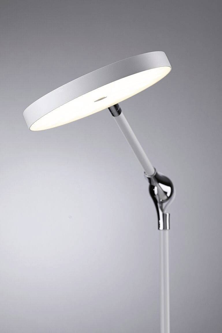Lampadaire moderne avec corps lumineux rond et plat en argent et blanc, inclinable sur un support élancé chromé.
