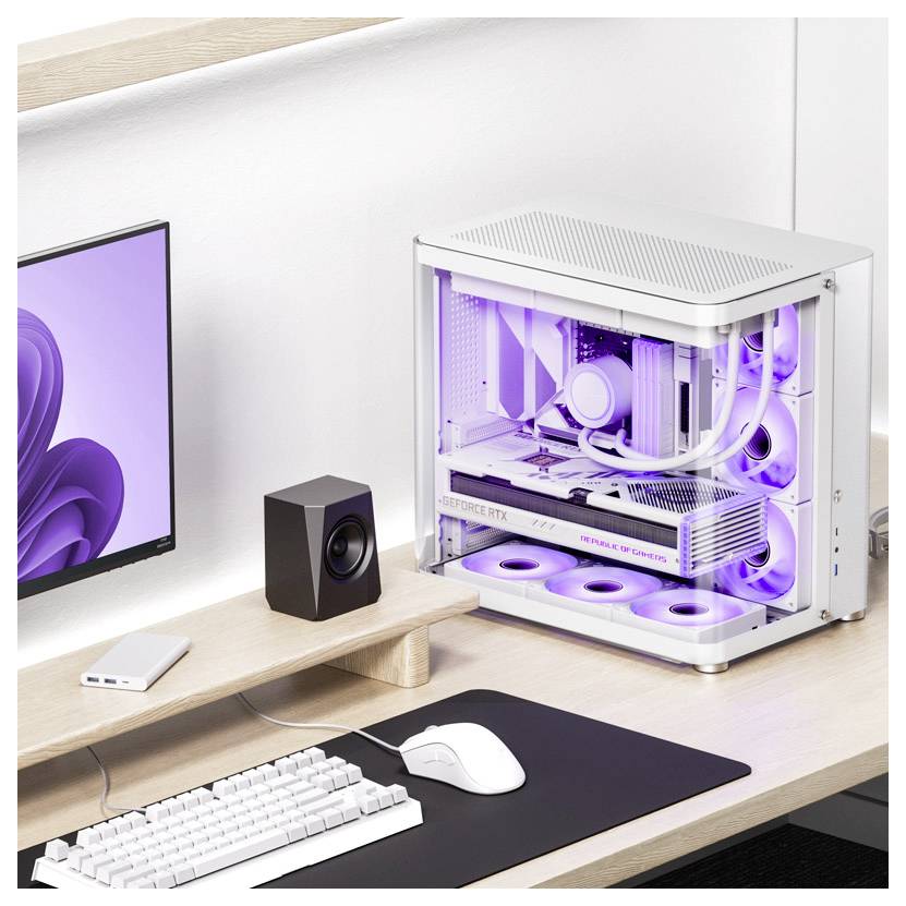 Un poste de travail informatique moderne avec un boîtier d'ordinateur rétroéclairé en violet, un écran, des enceintes, une souris et un clavier sur un bureau.