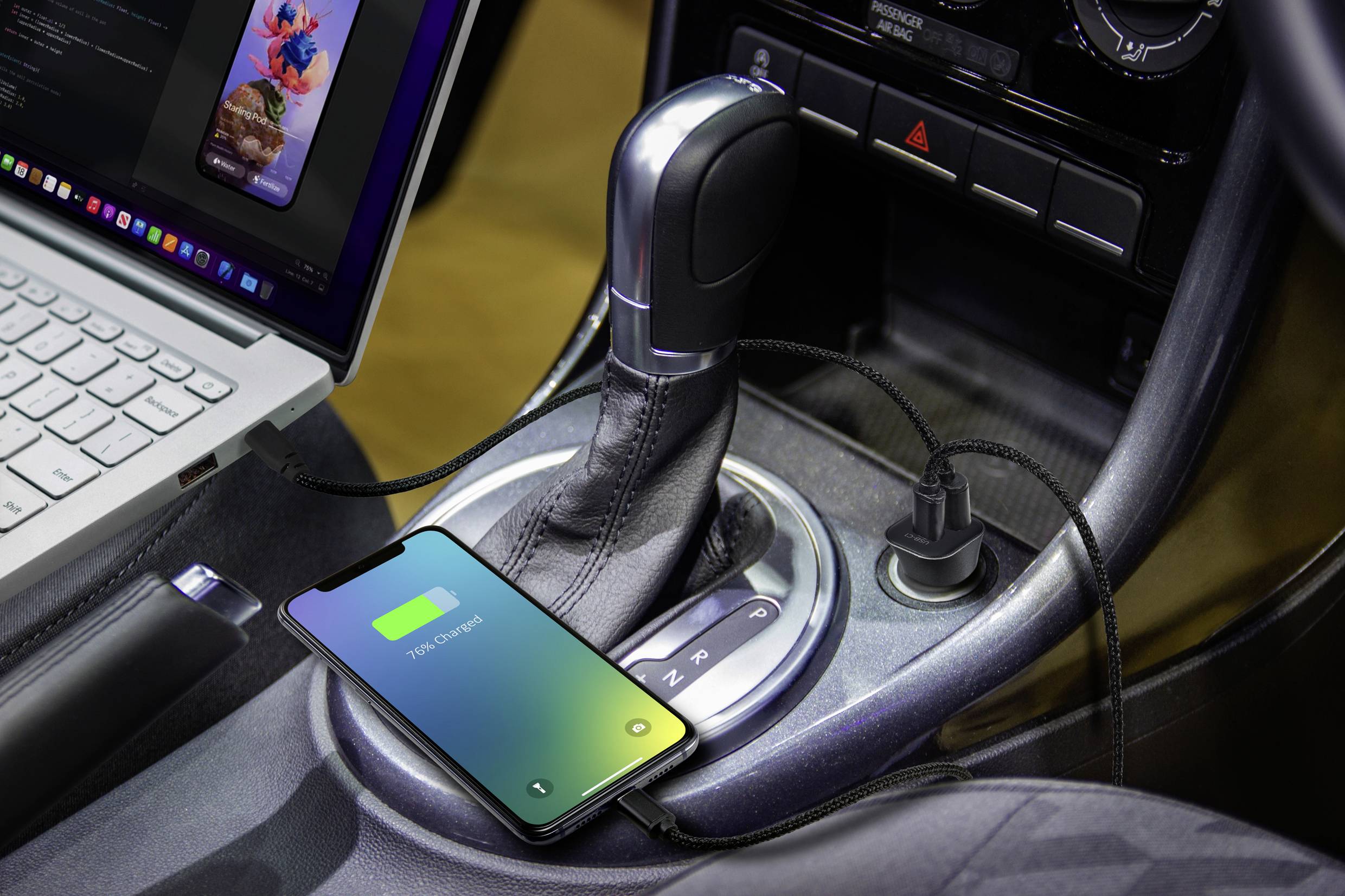 Un smartphone se charge dans la voiture, connecté par un câble USB à côté d'un ordinateur portable sur la console centrale.