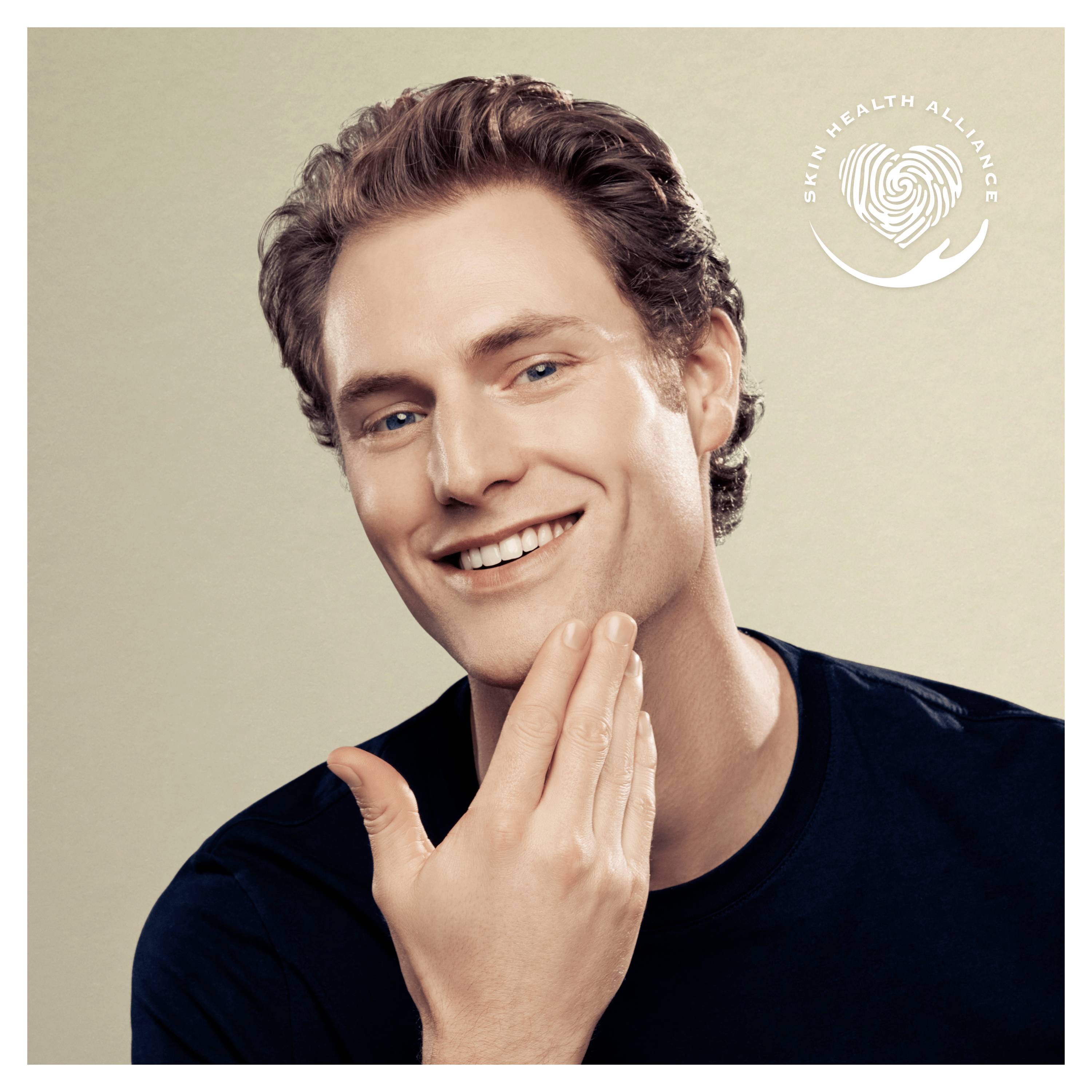Un homme souriant se touche le visage, le logo de la 'Skin Health Alliance' en arrière-plan.