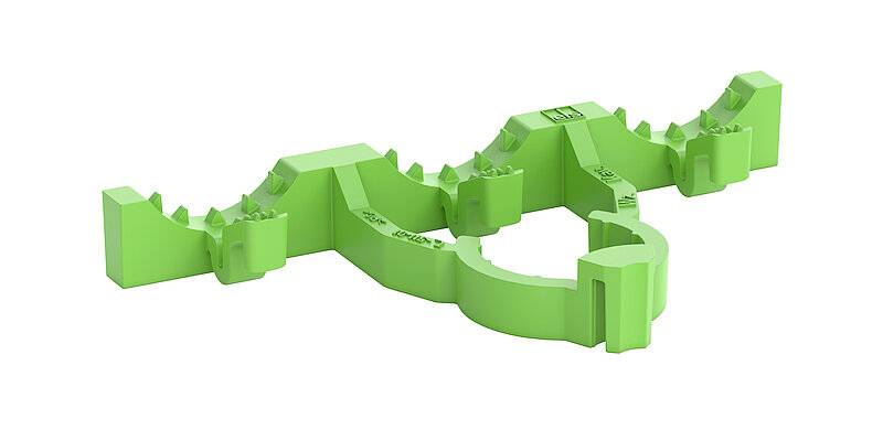 Pièce en plastique vert avec des bords et des dents irréguliers, potentiellement destinée à des applications techniques ou industrielles.