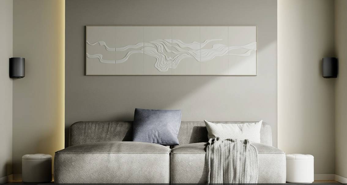 Un salon moderne avec un canapé gris, décoré de coussins blancs et gris. Un tableau abstrait est accroché au mur.