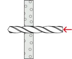 Une mèche pénètre horizontalement dans une planche verticale, une flèche rouge pointe vers la pointe de la mèche, la planche présente plusieurs trous réguliers.