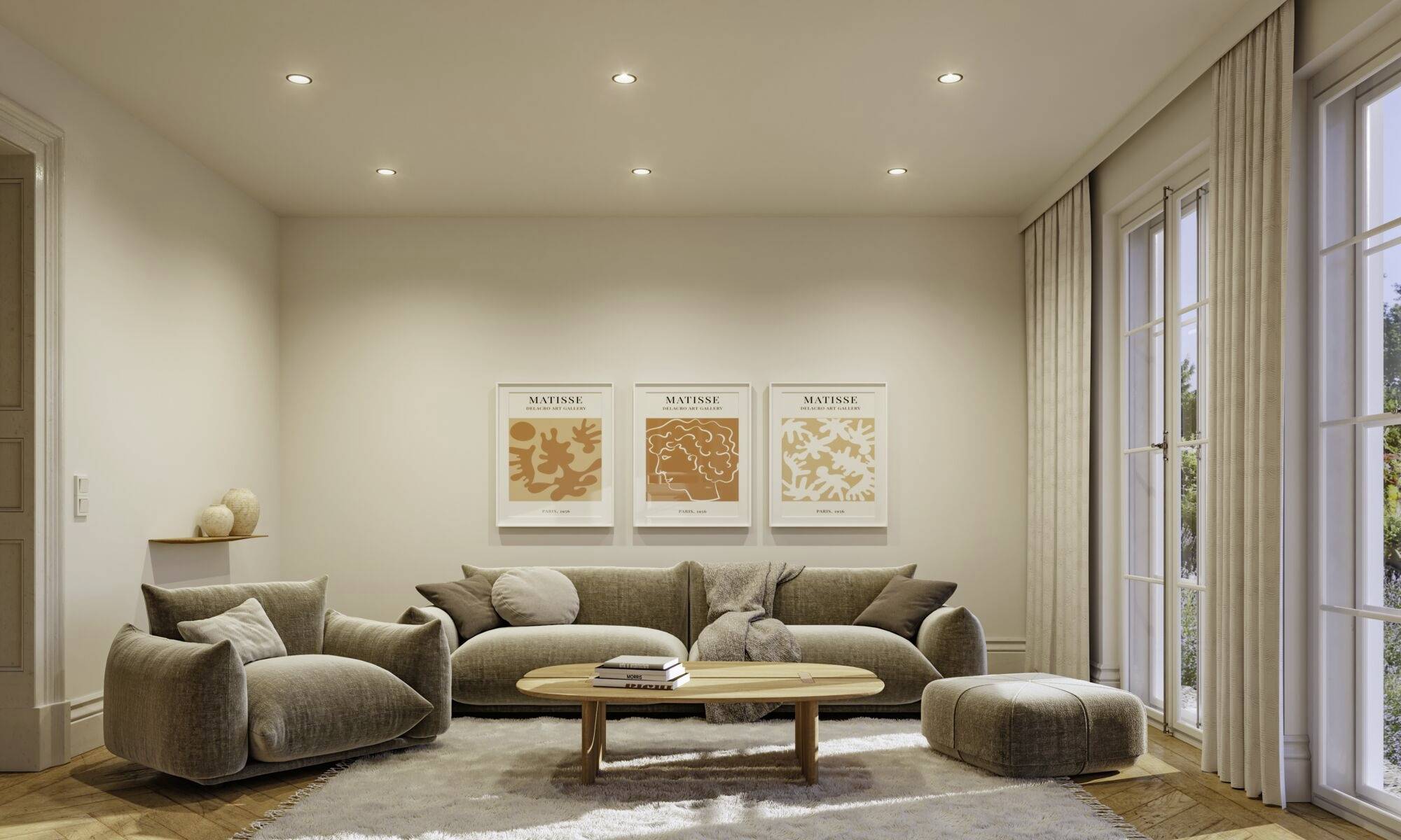 Salon avec un canapé gris, deux fauteuils, une table en bois et trois tableaux muraux. Des murs clairs et de grandes fenêtres apportent beaucoup de lumière.