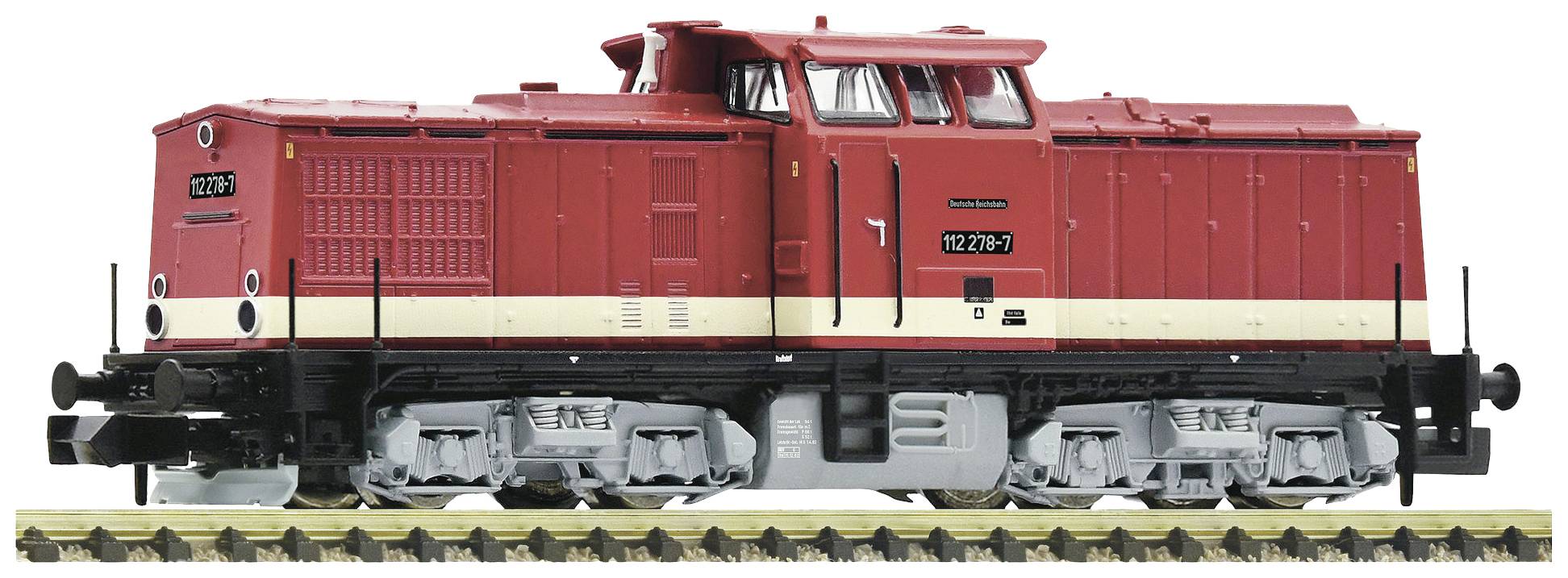 Locomotive rouge sur une voie ferrée, vue de côté. Identifiable par le numéro '112 276-7'.