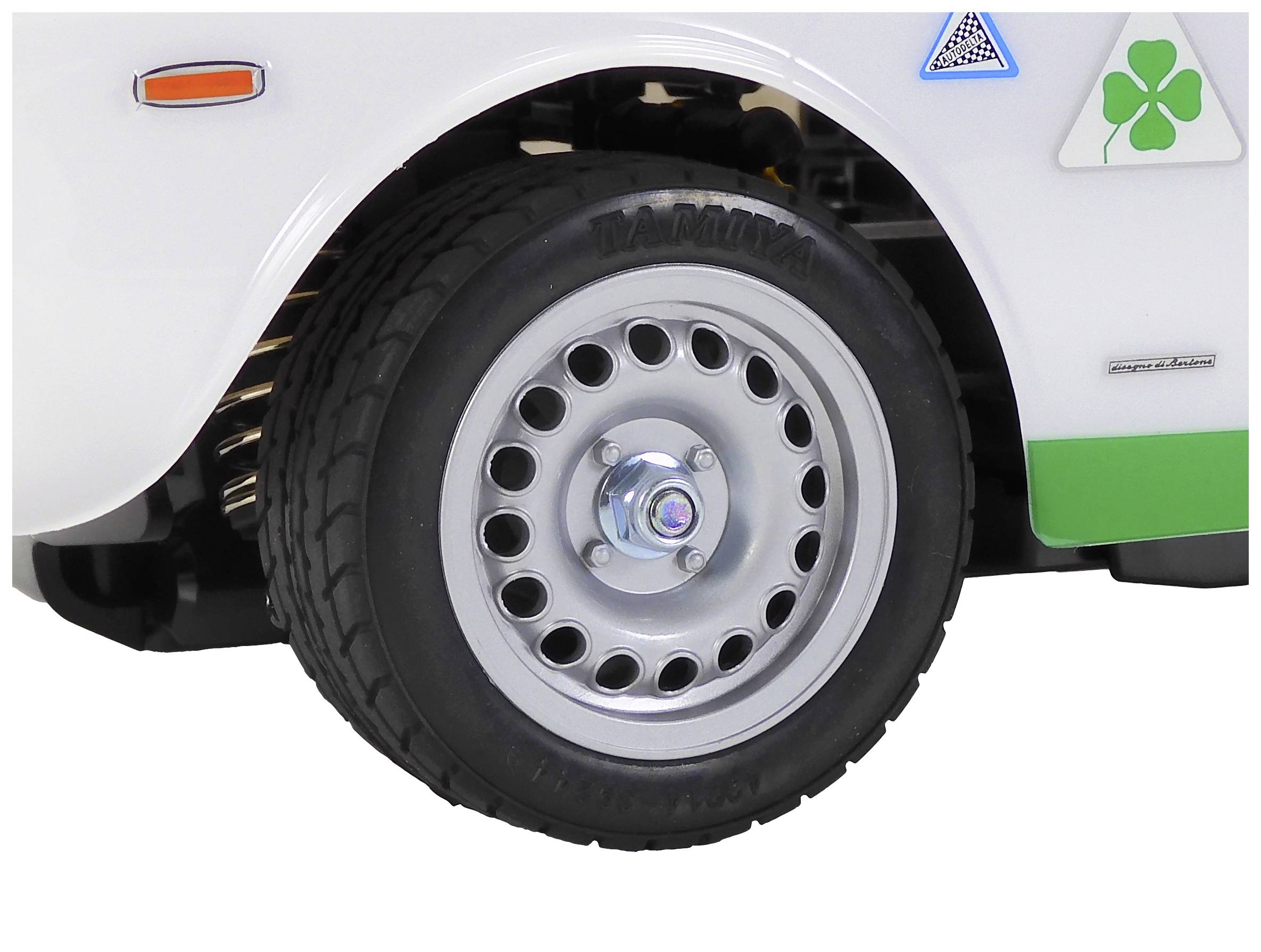 L'avant d'un véhicule blanc avec une roue et une jante. Un emblème en forme de trèfle vert est visible.