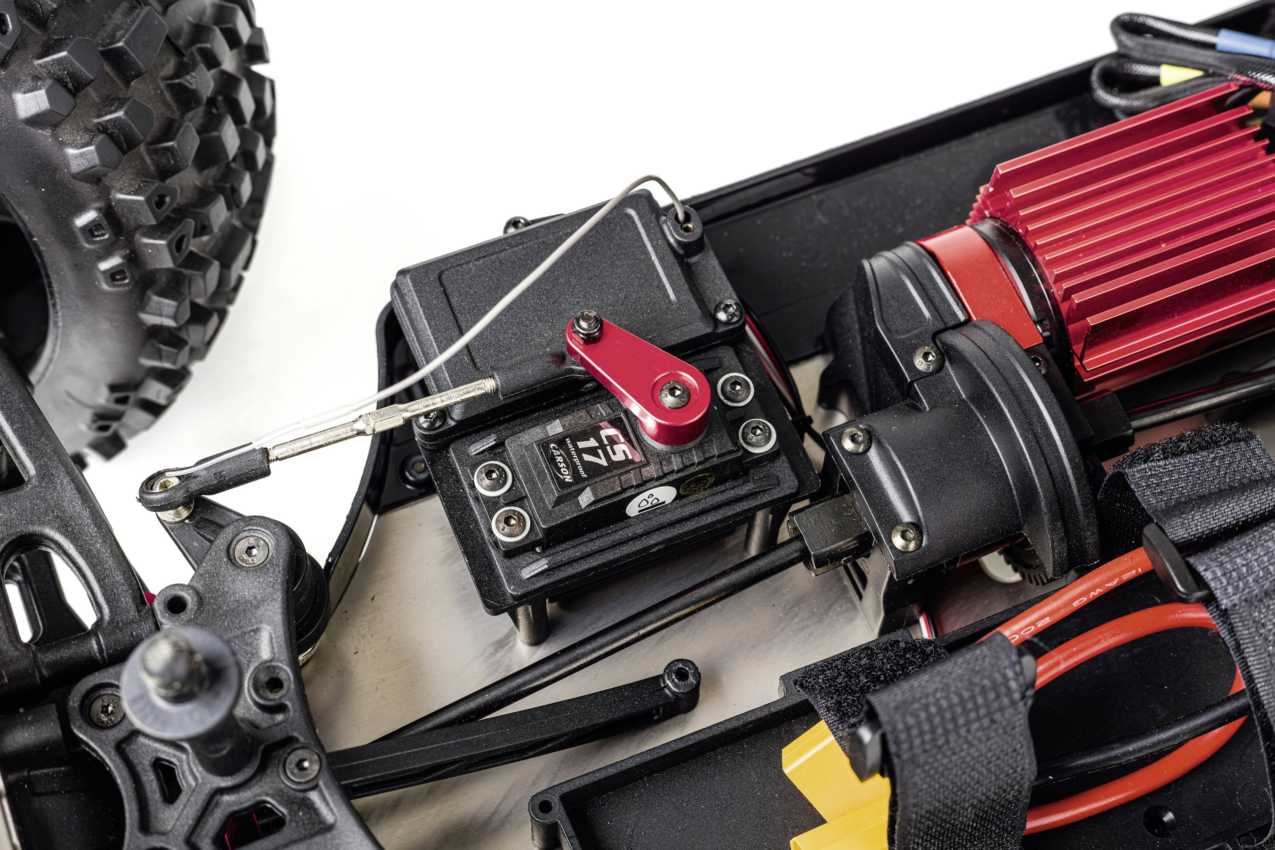 Gros plan d'une voiture télécommandée montrant des pièces de la transmission et du moteur avec quelques câbles et supports.