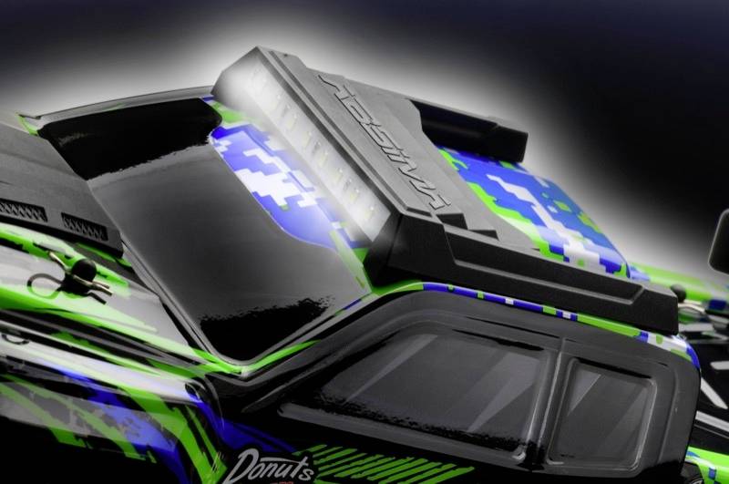 Une voiture télécommandée avec un motif de camouflage bleu-vert et des accents noirs. Sur le toit est inscrit 'AMASSADOR'.
