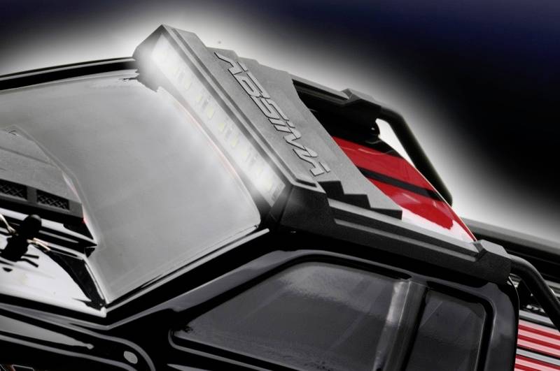 Voiture miniature avec un porte-bagages éclairé sur un fond de carrosserie rouge brillant.