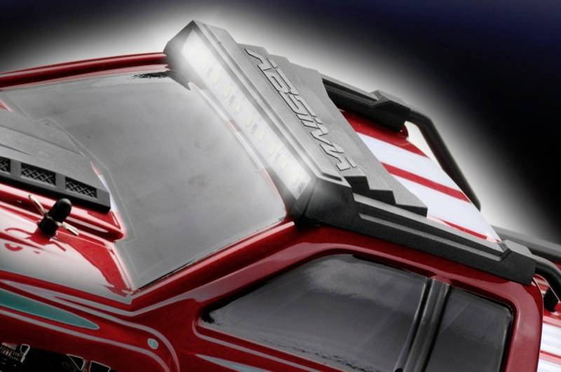 Gros plan d'une voiture miniature rouge avec un phare de toit détaillé. La voiture présente des bandes blanches et un capot de toit noir.