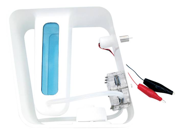 Un modèle de micro-centrale hydroélectrique avec réservoir d'eau, turbine et pinces crocodiles rouges et noires pour des expériences de production d'électricité.