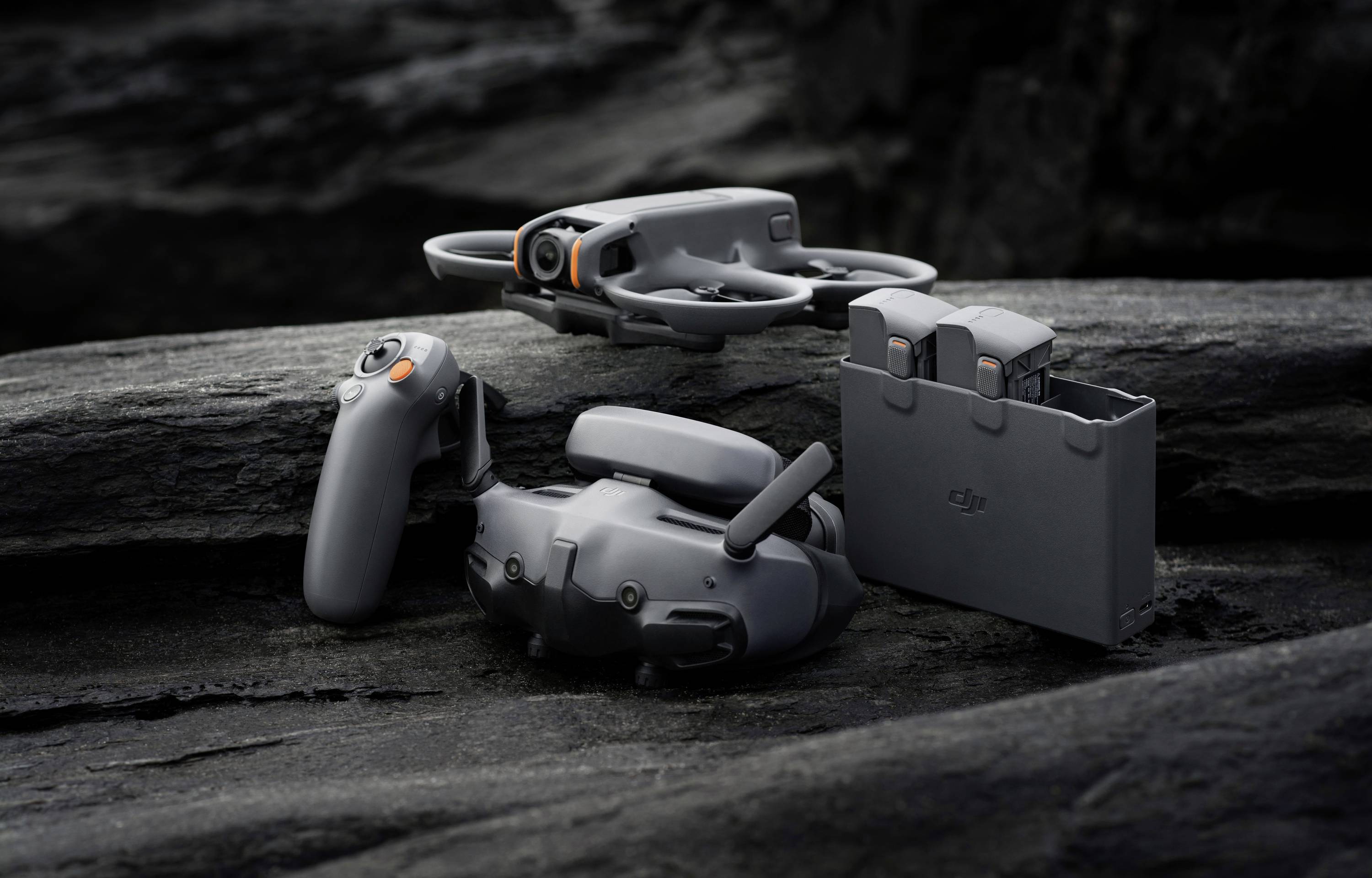 Drone télécommandée avec deux batteries de rechange sur un terrain rocailleux, prêt à voler.