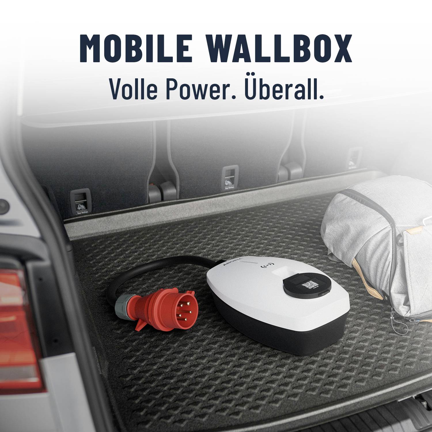 Wallbox mobile dans le coffre d'une voiture avec un connecteur rouge et un sac gris, texte : 'Pleine puissance. Partout.'