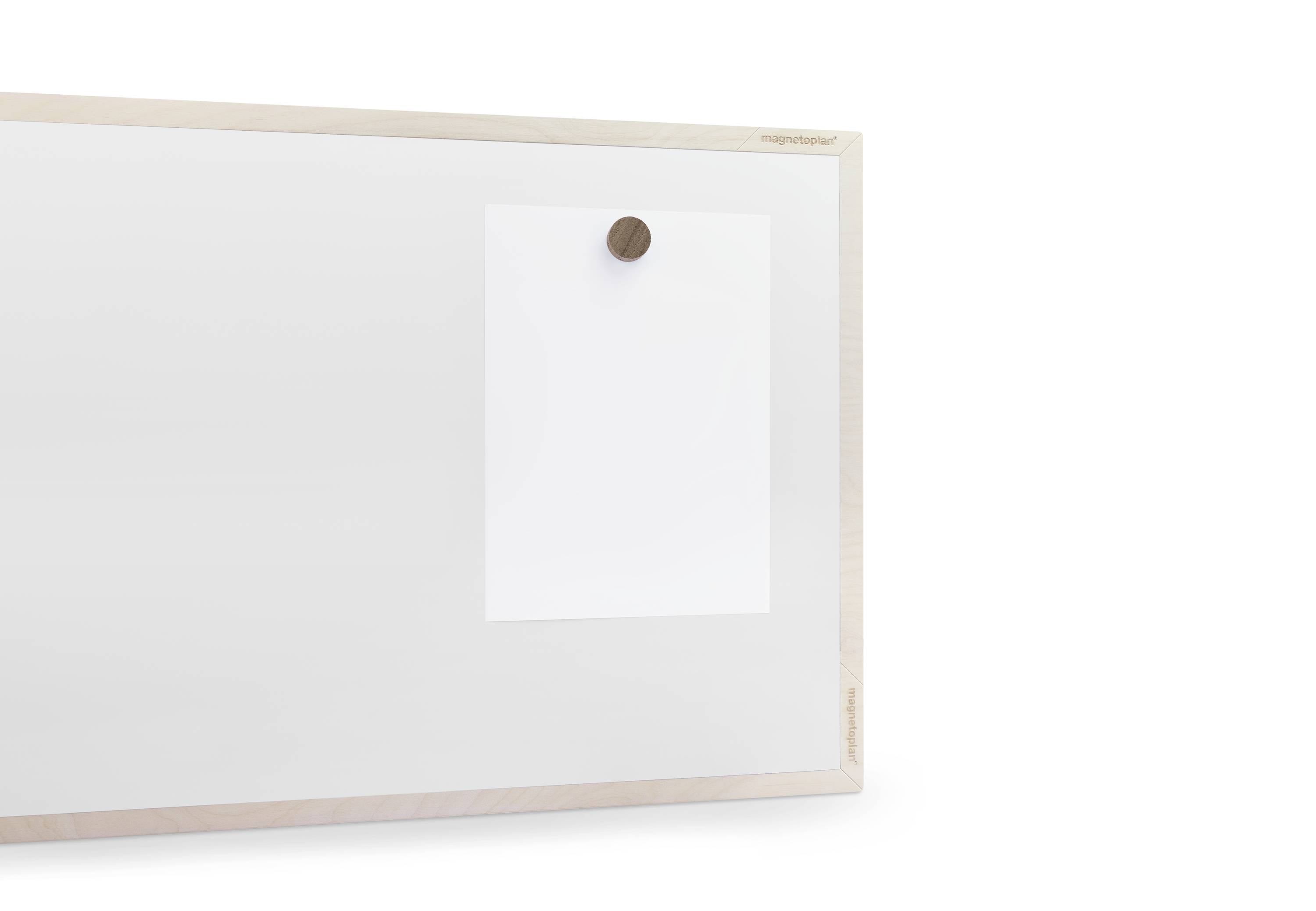 Tableau blanc magnétique avec cadre en bois, sur lequel est fixée une feuille de papier blanche à l'aide d'un aimant rond de couleur brune.