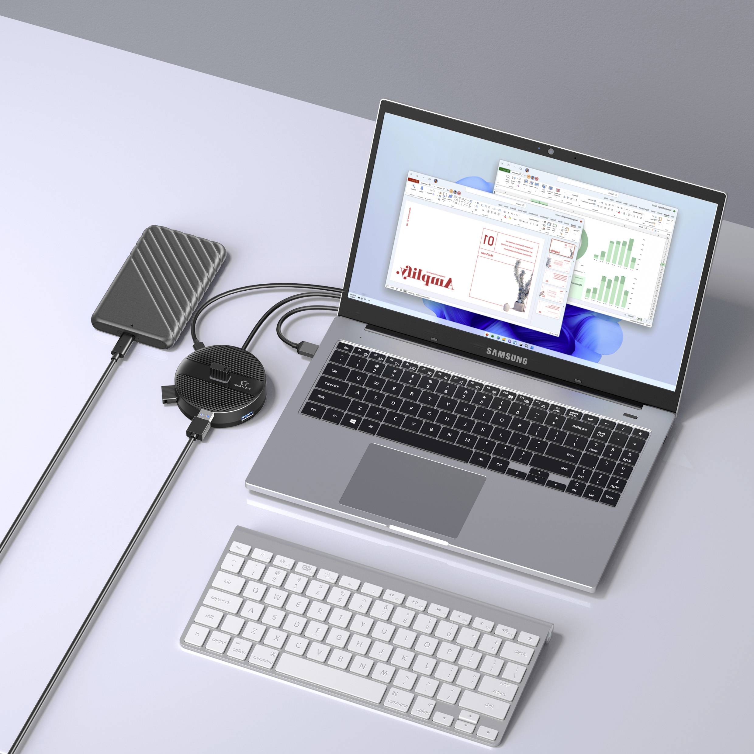 Un ordinateur portable ouvert affiche des graphiques commerciaux sur son écran. À côté se trouvent un disque dur externe, un hub USB et un clavier.