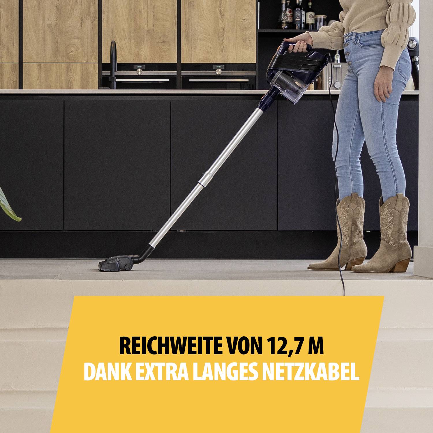 Une femme aspire le sol avec un aspirateur ; le texte souligne « portée de 12,7 m grâce à un câble d'alimentation extra-long ».