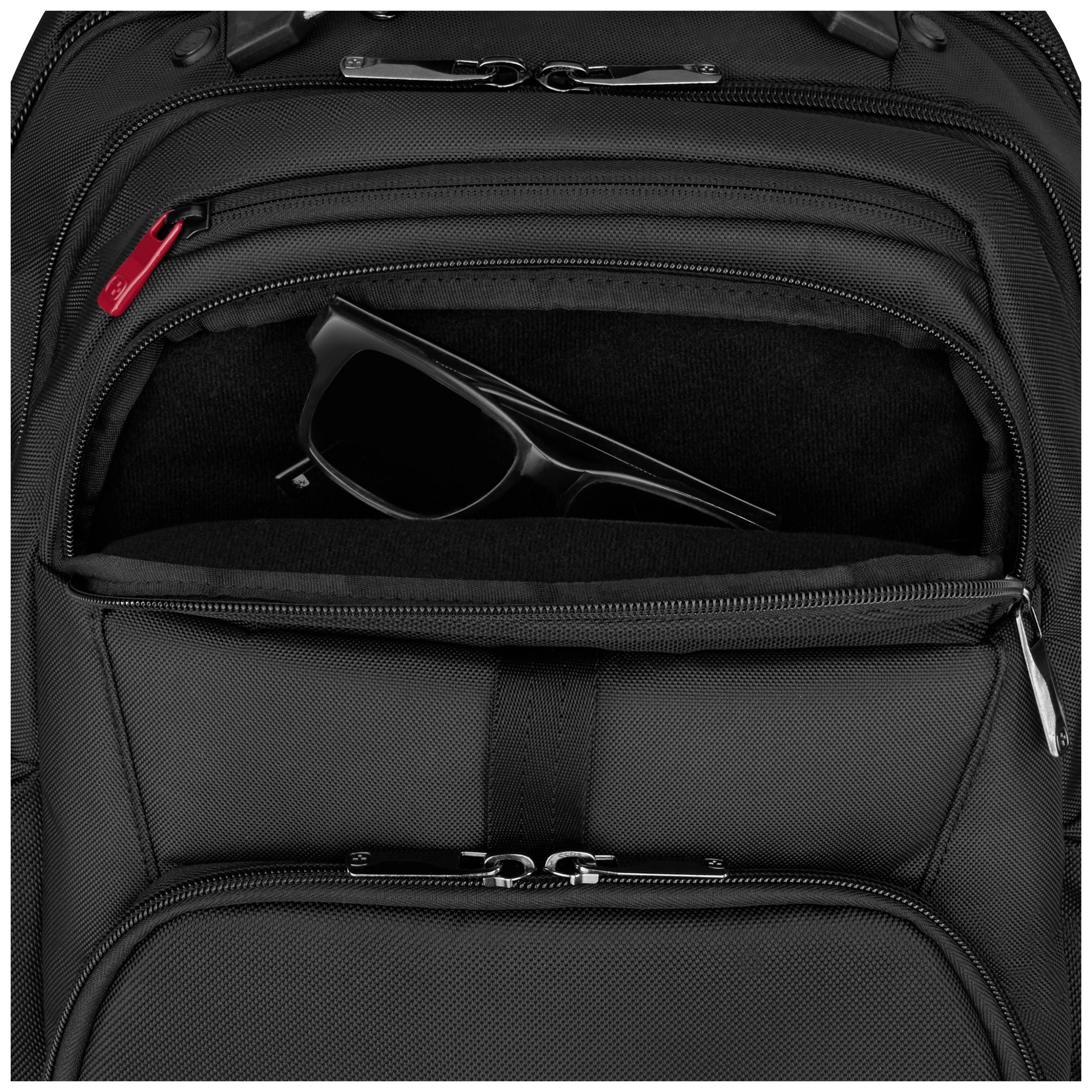 Un sac à dos noir en tissu avec une poche avant à moitié ouverte, dans laquelle une paire de lunettes de soleil noires est rangée.