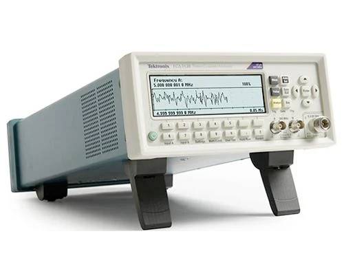 Un oscilloscope numérique affiche sur l'écran une mesure de fréquence avec une forme d'onde. De nombreux éléments de commande sont visibles.
