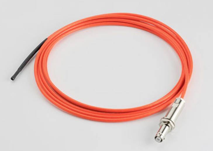 Un câble rouge avec une fiche métallique, enroulé sur un fond blanc. Utilisé pour des connexions électriques.