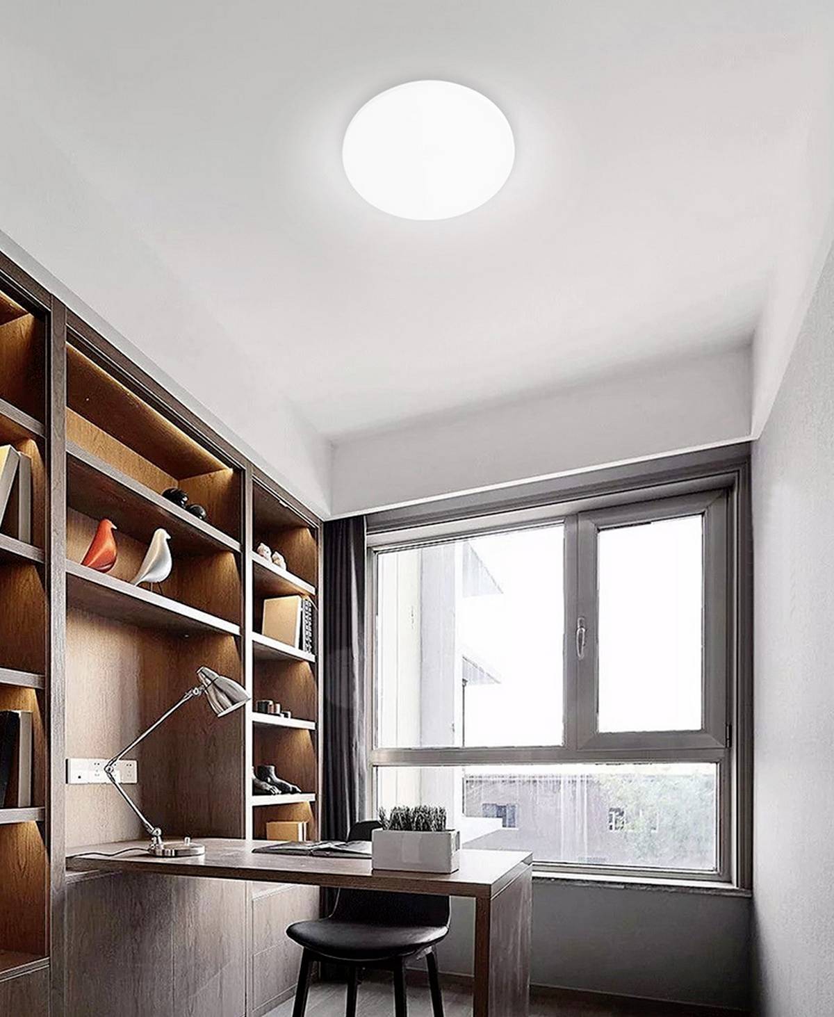 Un bureau à domicile moderne avec des étagères en bois, un bureau, une lampe et une fenêtre donnant sur l'extérieur. Les étagères contiennent des objets décoratifs.