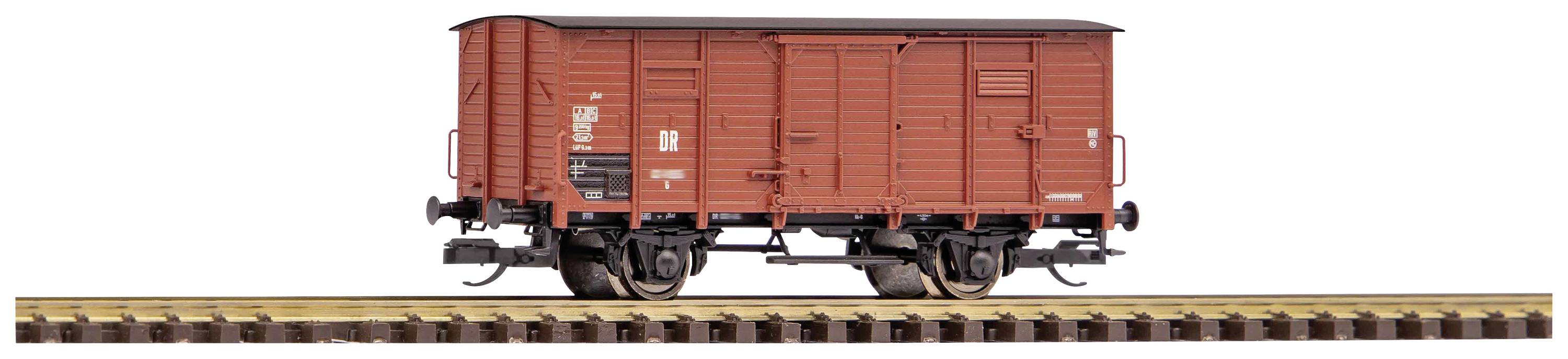 Wagon de marchandises brun sur une voie ferrée, vue latérale. Le wagon a une forme rectangulaire et des roues en métal.