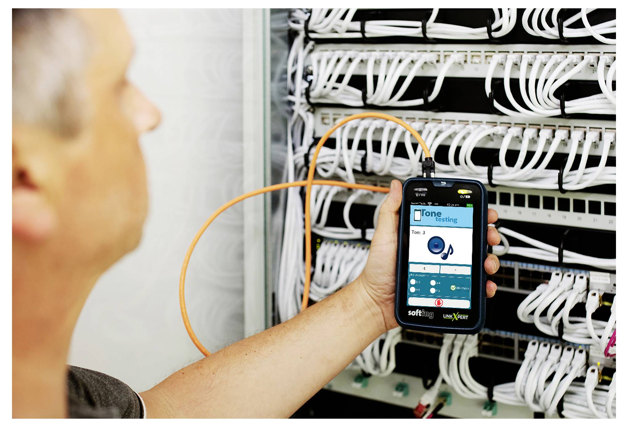 Techniker hält ein Smartphone, um Netzwerkkabel in einem Serverrack mit einer Überwachungs-App zu überprüfen.