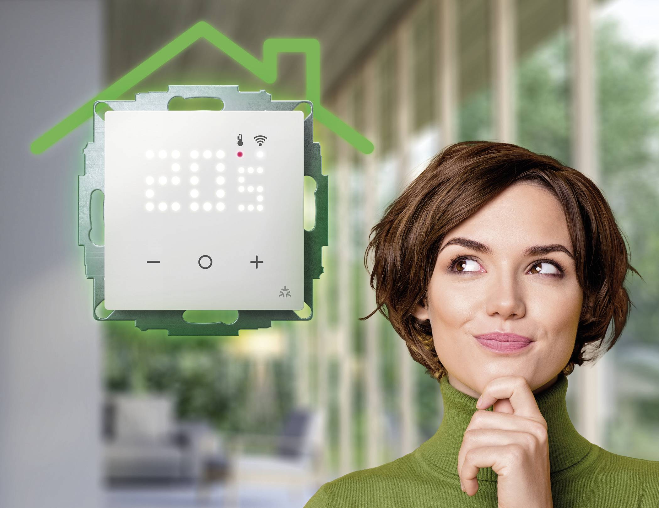 Une femme regarde pensivement un thermostat connecté affichant 20,5 degrés. Derrière elle se trouve une pièce au design moderne.