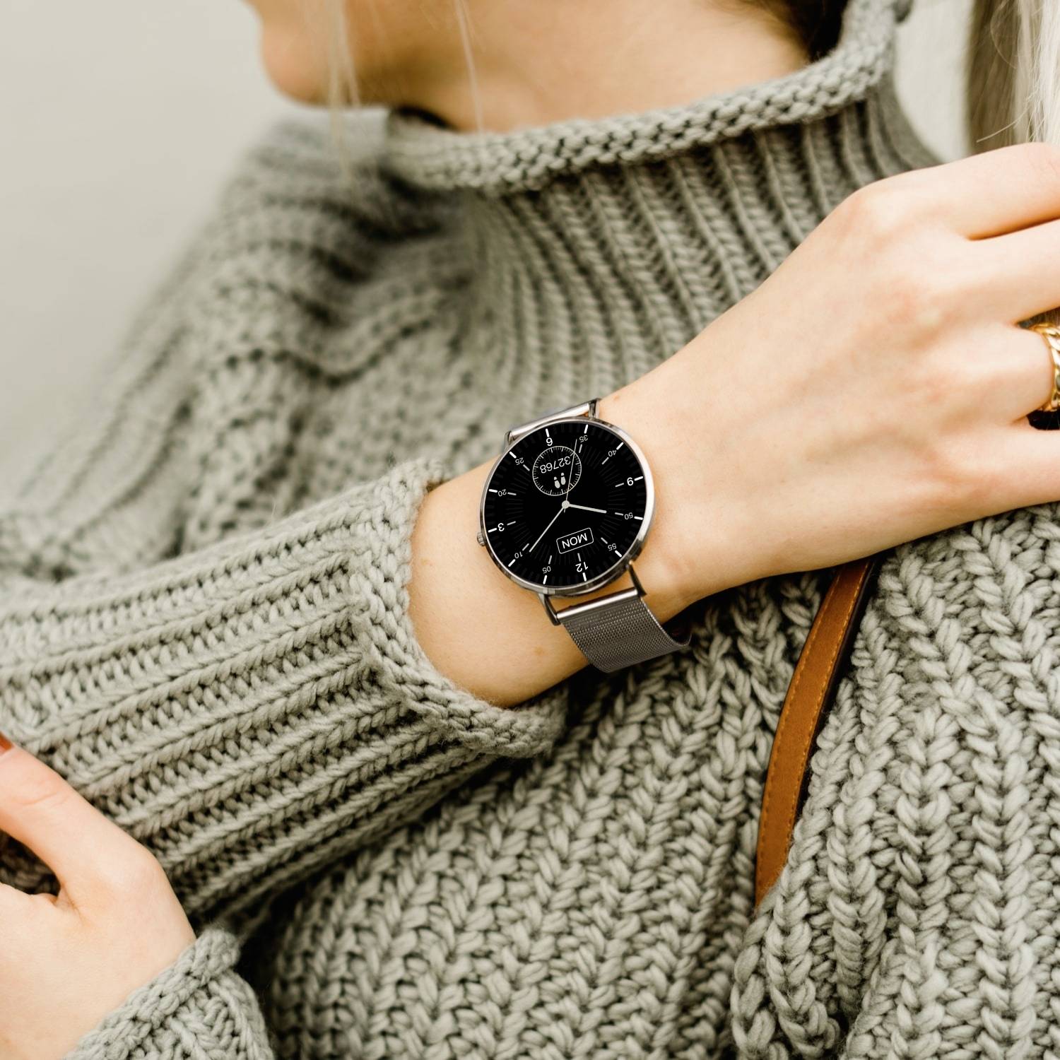 Une personne porte un pull gris et une montre-bracelet noire à affichage numérique.