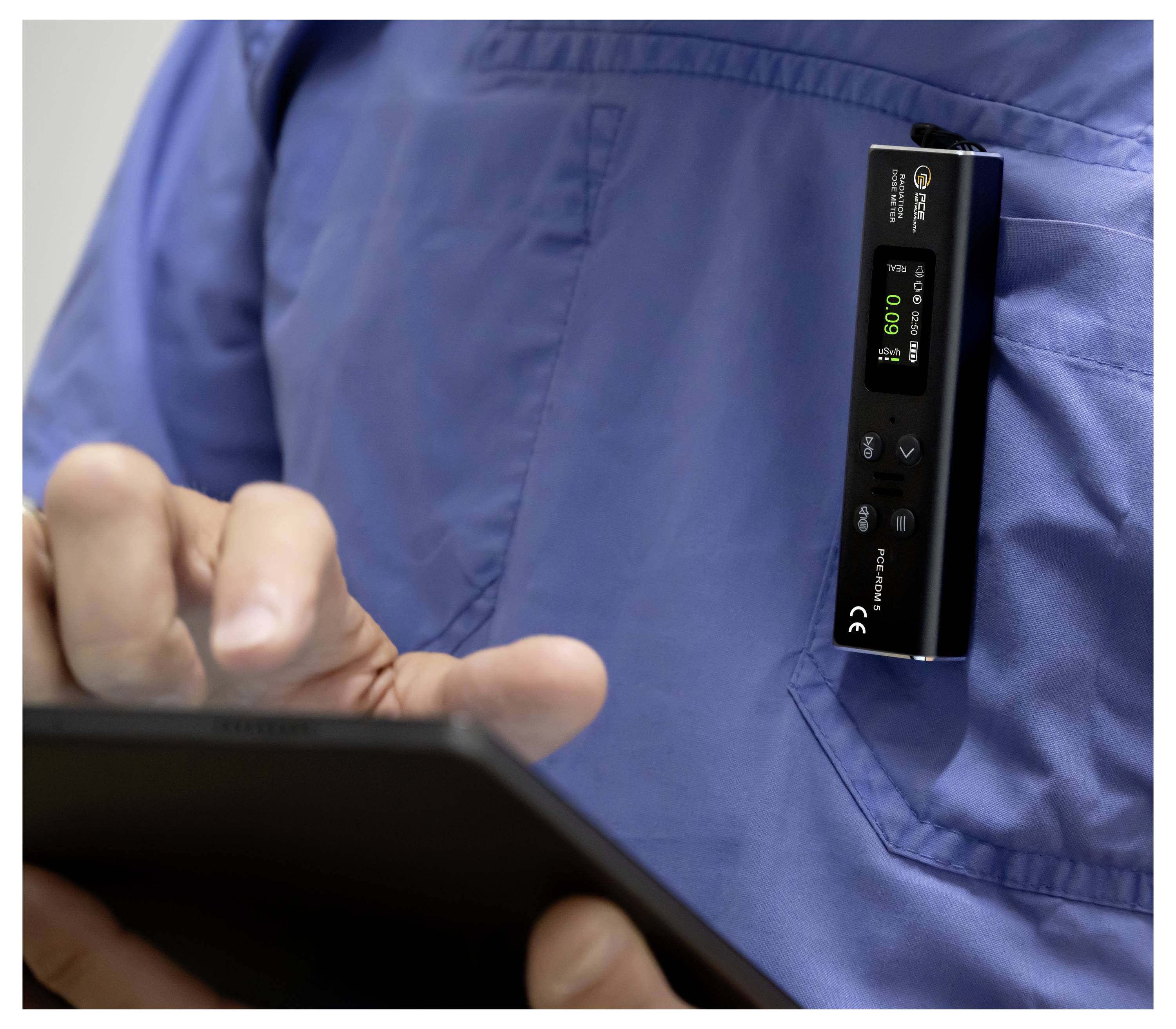 Infirmière en uniforme bleu utilise une tablette tandis qu'un moniteur portable à clip affiche une lecture numérique verte.