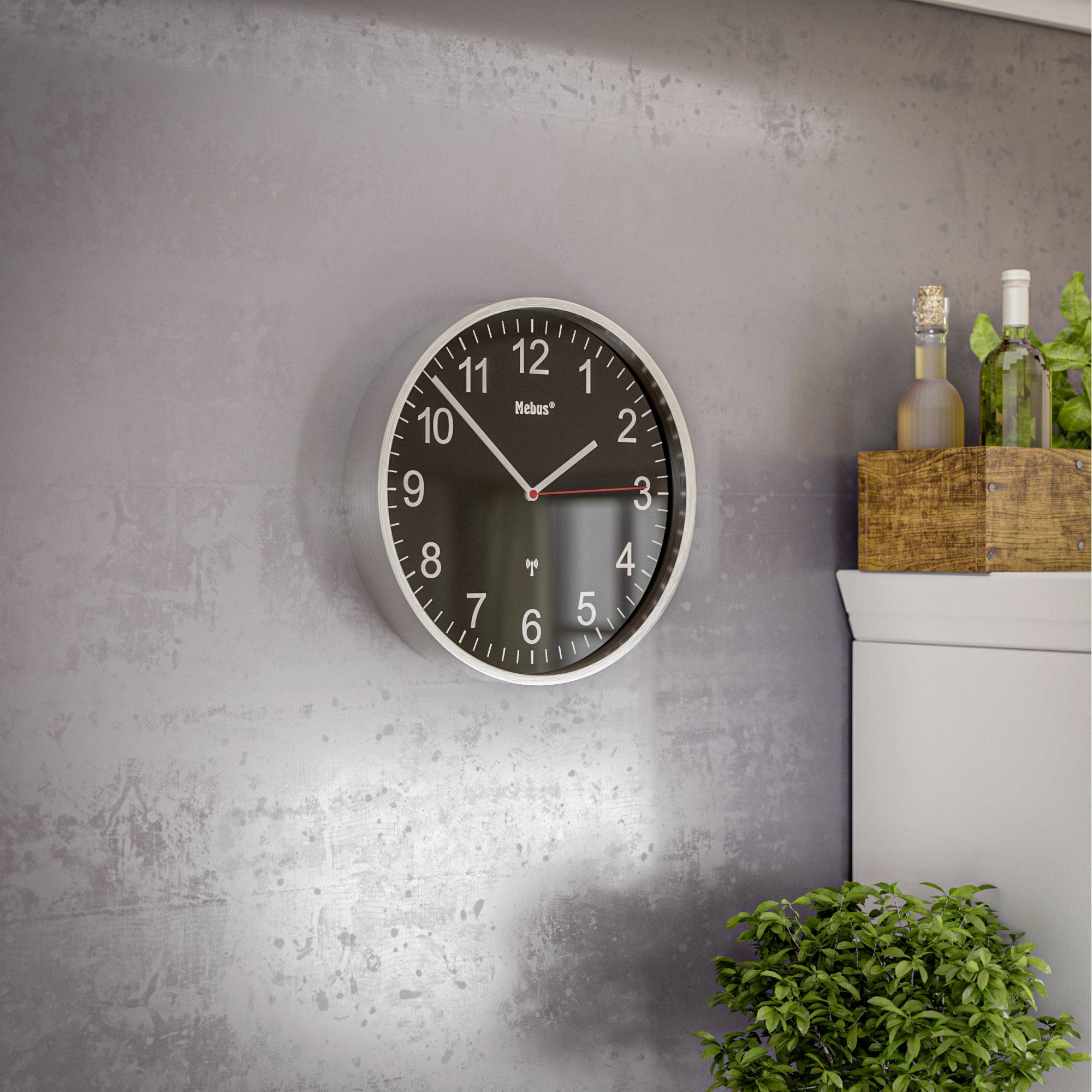 Une horloge murale avec un cadran noir indique 10h09. À côté se trouve une caisse avec des bouteilles et un buisson vert.