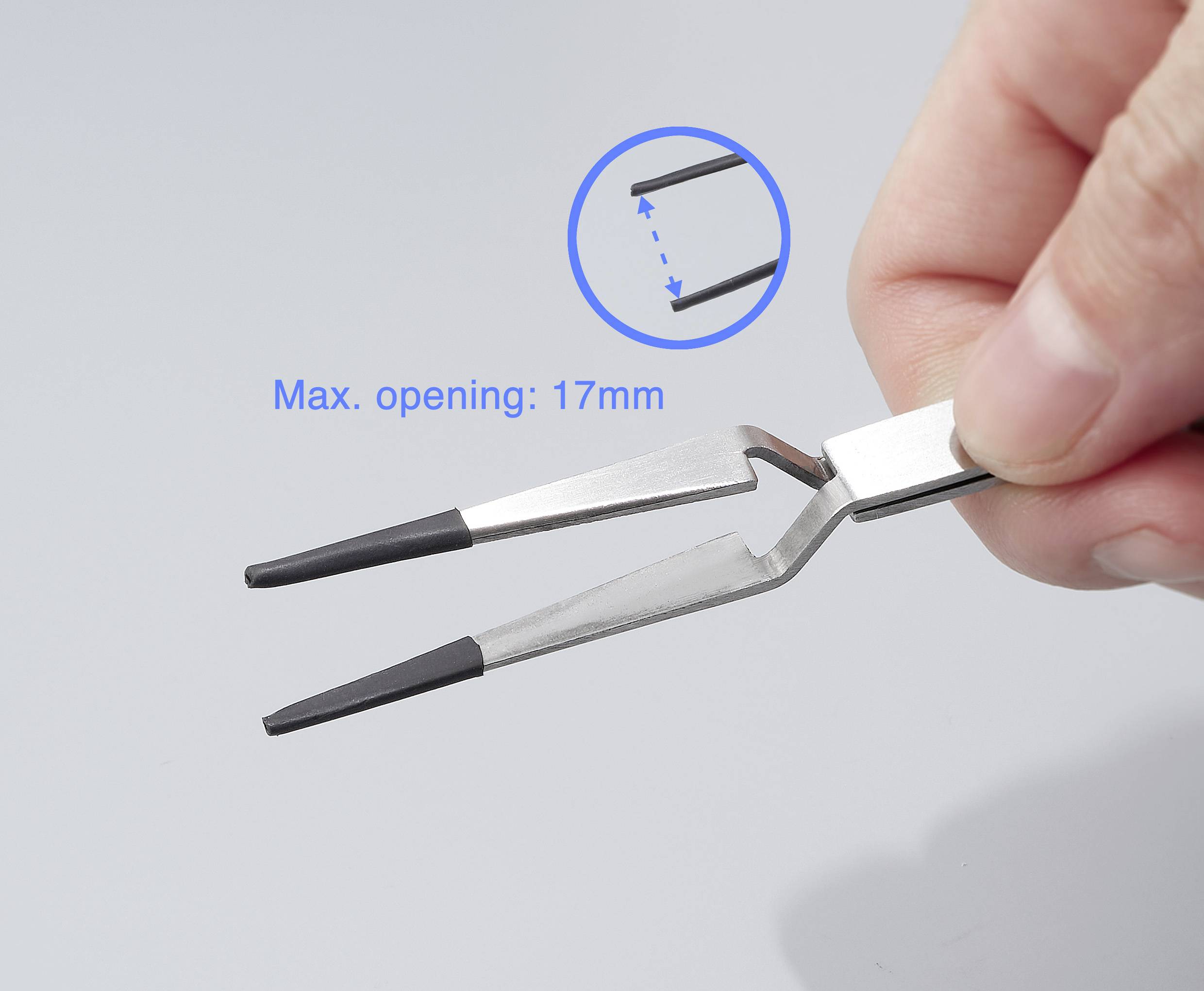 Une main tient une pince à deux branches. L'angle d'ouverture maximal est de 17 mm. Un zoom circulaire montre la connexion des pointes.