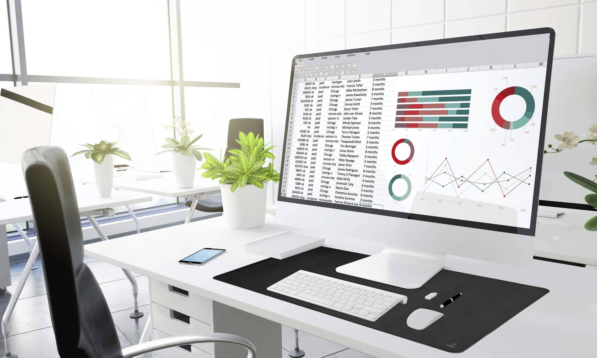 Un espace de bureau moderne et lumineux avec un grand écran affichant des tableaux et des graphiques de données de vente. Des plantes sont disposées sur le bureau.